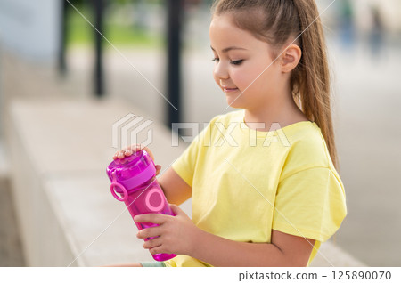 Little girl drinking water from bottle while enjoying summer outdoor activity 125890070