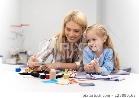 Mom and kid looking busy while choosing threads for sewing 125890162