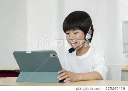 A fourth grade boy wearing a headset and facing a tablet PC 125890419