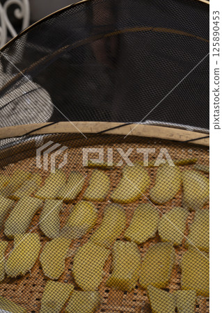 The process of making dried sweet potatoes. Sweet potatoes are lined up on a drying rack and dried in the sun. The process of making dried sweet potatoes. Sweet potatoes are lined up on a drying rack and dried in the sun. 125890453