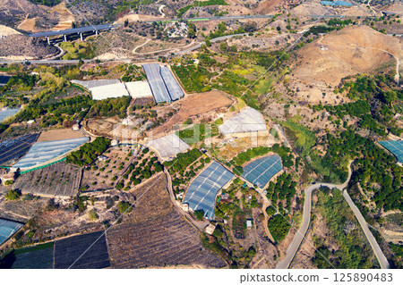 Top view of greenhouses in a mountainous area. Maro, Malaga, Spain. The Manantial Viaduct on the left top corner 125890483