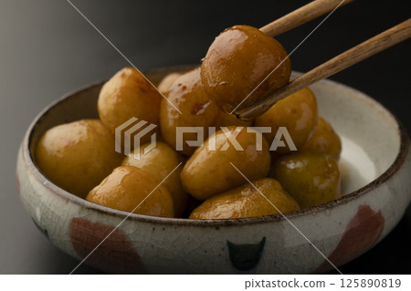Picking up boiled small potatoes with their skins on using chopsticks Picking up boiled small potatoes with their skins on using chopsticks 125890819