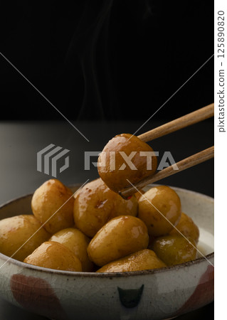 Picking up boiled small potatoes with their skins on using chopsticks Picking up boiled small potatoes with their skins on using chopsticks 125890820