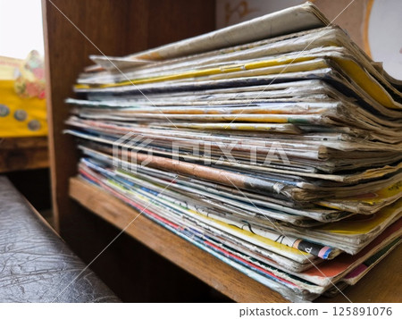 Closeup of a messy pile of old magazines with bending pages. the old paper texture of many old folded magazines. A stack of old magazines. Library, old children's magazines. Closeup of a messy pile of old magazines with bending pages. the old paper texture of many old folded magazines. A stack of old magazines. Library, old children's magazines. 125891076