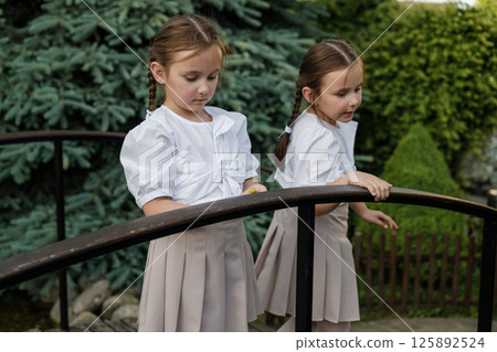 Twin girls by the railing. The snail becomes the center of attention for both children. 125892524