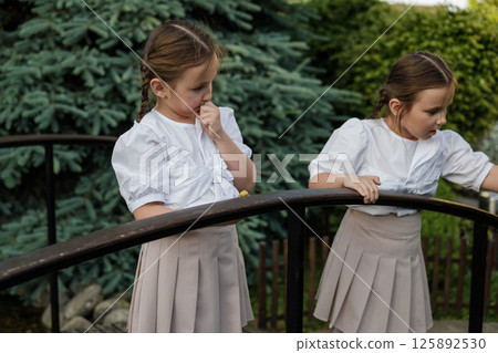 Little girls intently watch the snail. The twins stand side by side.  125892530