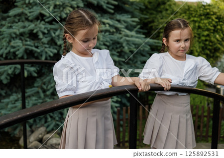 Little girls intently watch the snail. The twins stand side by side. Little girls intently watch the snail. The twins stand side by side. 125892531