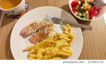 Healthy dinner with fish, pasta, cheese sauce, and salad with vegetable broth 125893110