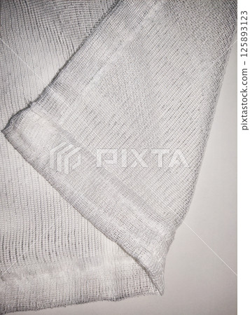 Soft textured gray fabric with intricate knit pattern draping elegantly, showcasing delicate craftsmanship and inviting warmth for cozy interior decor 125893123