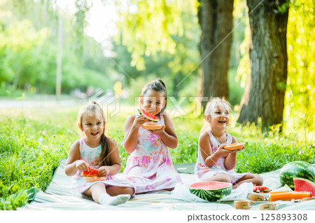A group of children eating watermelon on the street.  125893308