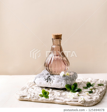 Beautiful pink transparent bottle of perfume with flowers 125894078
