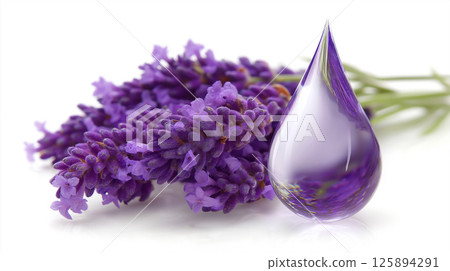 A large shimmering purple drop sits gracefully next to vibrant lavender flowers. The drop captures light beautifully, showcasing its glossy surface. The setup evokes a serene floral atmosphere. 125894291
