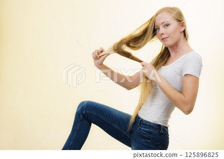 Blonde girl brushing her long hair 125896825