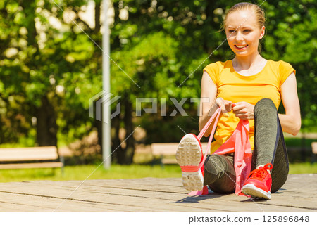 Girl doing exercise outdoor, using resistance fit band. 125896848