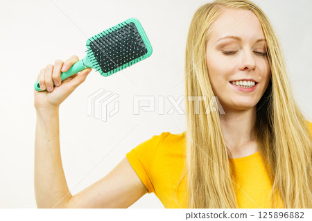 Blonde girl brushing her long hair 125896882