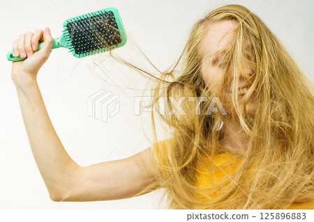 Blonde girl long tangled hair holds brush 125896883