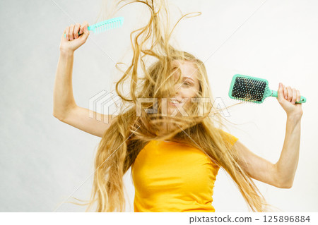 Girl blowing hair with comb brush Girl blowing hair with comb brush 125896884
