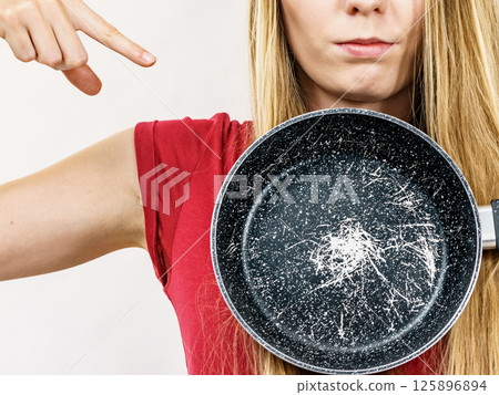 Girl holding scratched frying pan Girl holding scratched frying pan 125896894