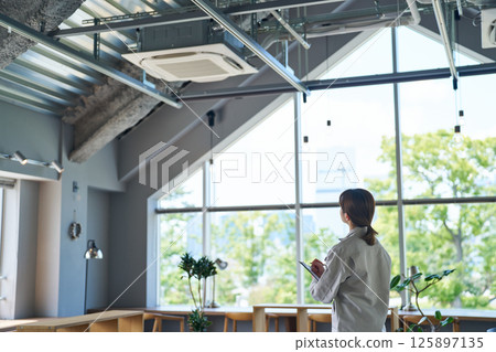 A woman inspecting an air conditioning unit 125897135