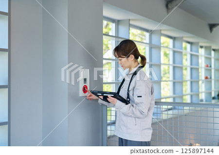 一名婦女檢查緊急警報設備 一名婦女檢查緊急警報設備 125897144
