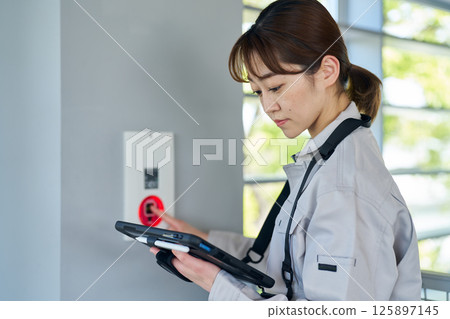 A woman inspecting emergency alarm equipment 125897145