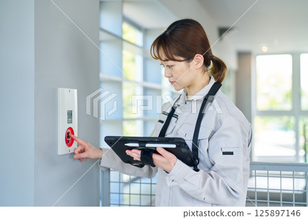 一名婦女檢查緊急警報設備 一名婦女檢查緊急警報設備 125897146