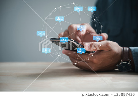 Mans hand engaged with smartphone, typing live chat and social network concepts. Home office setting, chat box icons emerging, exemplify modern communication trends. Social media marketing technology Mans hand engaged with smartphone, typing live chat and social network concepts. Home office setting, chat box icons emerging, exemplify modern communication trends. Social media marketing technology 125897436