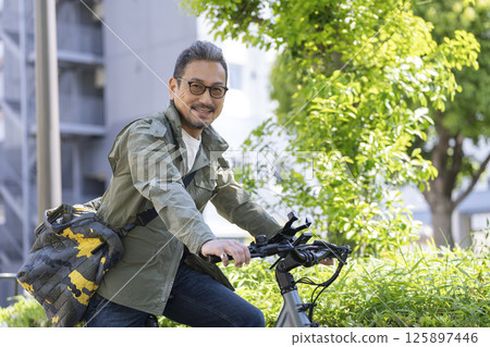 A man in his late 50s on a bicycle smiling at the camera 125897446