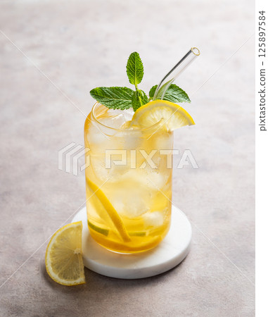 Iced tea with lemon and mint in a glass on a light background with citrus slice. 125897584