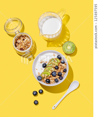 Natural yogurt with granola, kiwi and blueberries in a bowl on a bright yellow background Natural yogurt with granola, kiwi and blueberries in a bowl on a bright yellow background 125897595