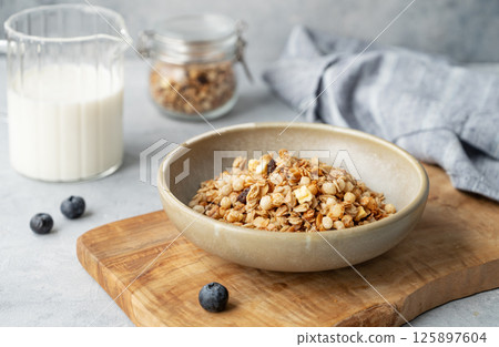Homemade baked granola or muesli in a bowl on a wooden board on a light background 125897604
