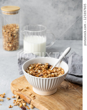 Homemade baked granola or muesli in a bowl on a wooden board on a light background Homemade baked granola or muesli in a bowl on a wooden board on a light background 125897605