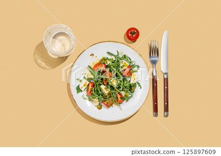 Fresh arugula salad with cherry tomatoes, mozzarella, pesto sauce on yellow background 125897609