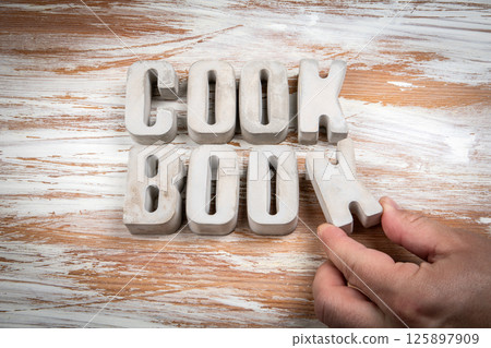 Cook Book. Concrete alphabet letters on a light painted wood texture background Cook Book. Concrete alphabet letters on a light painted wood texture background 125897909