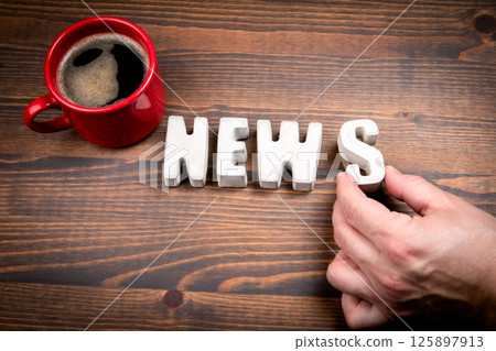 NEWS. Concrete alphabet letters and coffee mug on dark wooden texture background 125897913