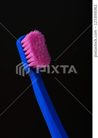 Used plastic toothbrush with pink bristles on black background. Germs. Time to throw it away and replace it with a new one. Used plastic toothbrush with pink bristles on black background. Germs. Time to throw it away and replace it with a new one. 125898062