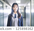 一名身穿校服、微笑的女學生站在學校走廊裡 125898162