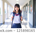 一名身穿校服、微笑的女學生站在學校走廊裡 125898165