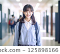 一名身穿校服、微笑的女學生站在學校走廊裡 125898166