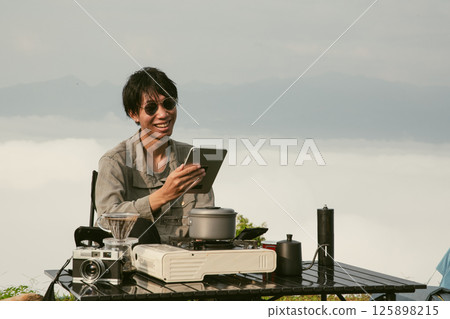 Young business man working computer on peak hill. Hiker online shopping on laptop at sunset, sunrise on top mountain, freelance person remote work with digital tablet. travel vacation holiday concept 125898215
