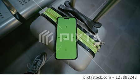 Airport Terminal: Mobile Phone with Green Chroma Key Display Mock Up Lying on Suitcase Airport Terminal: Mobile Phone with Green Chroma Key Display Mock Up Lying on Suitcase 125898248