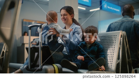 Mother with Two Little Kids Waiting for Airplane Flight, Boy Toddler Watching Cartoons on Digital Tablet 125898264