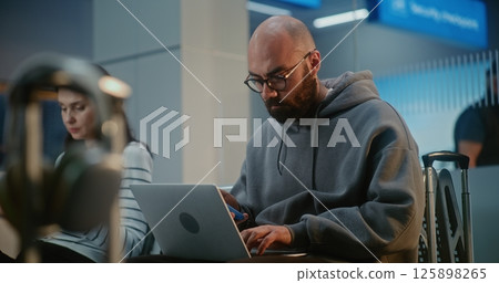 Airport Terminal: Entrepreneur Working Online on Laptop, Doing e-Business, Waiting for Flight Airport Terminal: Entrepreneur Working Online on Laptop, Doing e-Business, Waiting for Flight 125898265