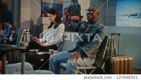 Man Talking by Video Chat, Filming Video Content Using Smartphone in Airline Hub Lounge Man Talking by Video Chat, Filming Video Content Using Smartphone in Airline Hub Lounge 125898301
