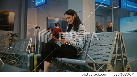 Airport Terminal: Happy Woman with Suitcase Sitting in Boarding Lounge After Security Check, 125898307