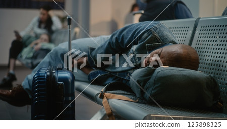 Crowded International Airport Terminal: Tired Tourist with Suitcase and Backpack Sleeping on the Seats 125898325