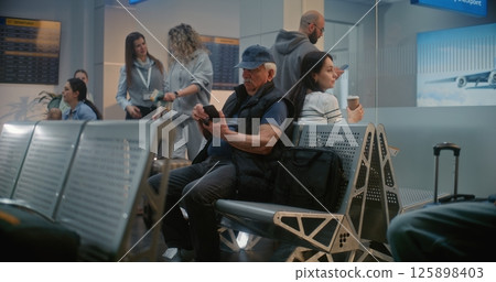 Airport Terminal: Diverse Tourists and Passengers Sitting in Departure Lounge of Crowded Airline Hub Airport Terminal: Diverse Tourists and Passengers Sitting in Departure Lounge of Crowded Airline Hub 125898403