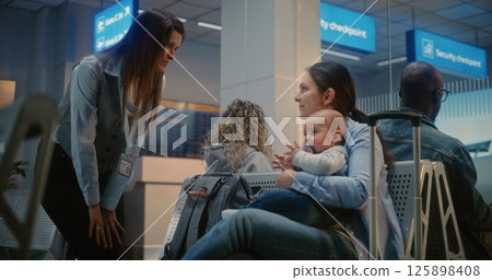 Airport Terminal: Adult Woman Sitting with Infant and Waiting for Airplane Flight 125898408