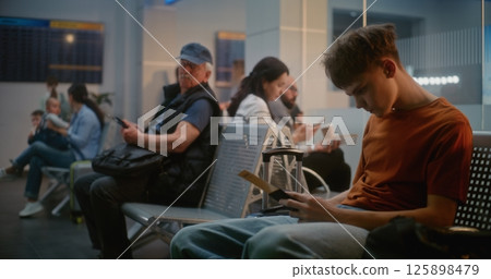 Diverse Passengers in Departure Lounge of Airline Hub. Teenage Boy Using Smartphone 125898479