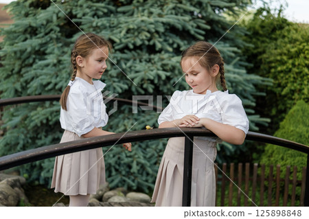 The twin girls are watching the snail's movement with interest. 125898848